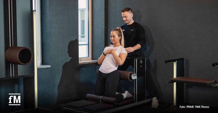 Ein Personal Trainer unterstützt eine Kundin bei ihrer Trainingsroutine im PRIME TIME fitness.