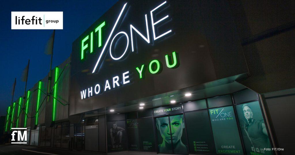 FIT/One Fitnessstudio bei Nacht mit leuchtendem Logo und moderner Glasfassade. Die Marke wird Teil der LifeFit Group und expandiert international